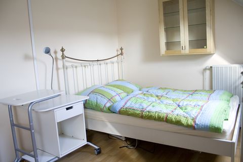 Zimmer 1: Bett mit Nachttisch und Hängeschrank